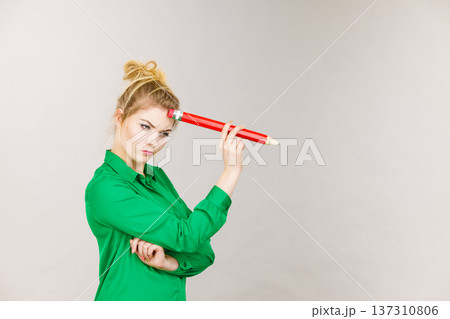 Woman confused thinking, big pencil in hand Woman confused thinking, big pencil in hand 137310806
