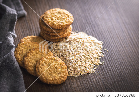 Cookies made with oats and oats scattered on wooden surface during daytime in a kitchen setting Cookies made with oats and oats scattered on wooden surface during daytime in a kitchen setting 137310869
