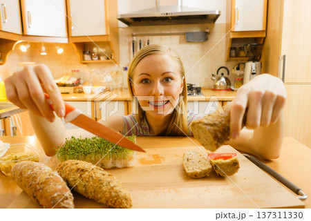 Woman in kitchen holding knife making healthy sandwich Woman in kitchen holding knife making healthy sandwich 137311330