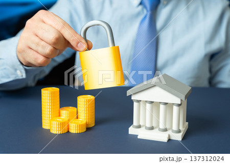 A bank and a padlock in the hands of a man in a tie. Bank protection and cybersecurity strategy ensuring data safety and secure financial transactions. 137312024