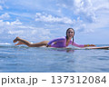Energetic Young Woman Navigates Surfboard Towards Distant Horizon 137312084