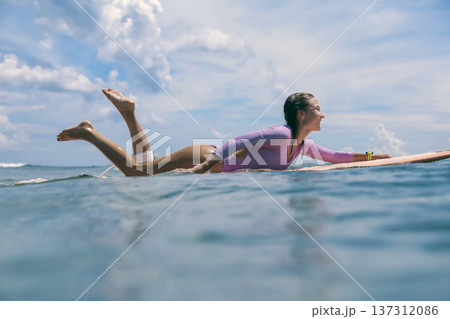 Woman Balances On Ocean Surf, Serene Scene Of Woman Paddling 137312086