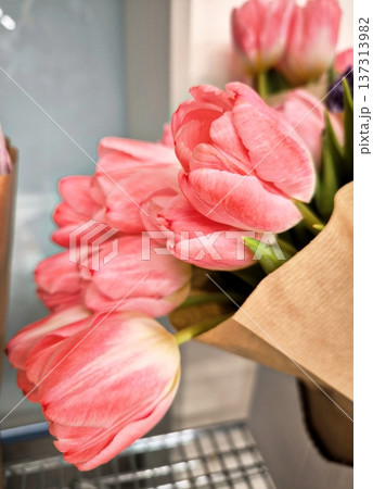 A close-up of a bouquet of soft pink tulips wrapped in craft paper A close-up of a bouquet of soft pink tulips wrapped in craft paper 137313982