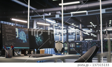 AI development workstation in data center with dual monitors displaying machine learning code. Server hub computers used for tracking neural network structures algorithm performance AI development workstation in data center with dual monitors displaying machine learning code. Server hub computers used for tracking neural network structures algorithm performance 137315133