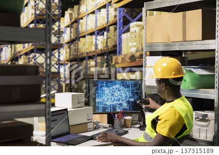 Black worker taking scanner to register shipping labels tracking info with AI brain, package tracking software helps handling online shopping orders with neural networks automation in warehouse. Black worker taking scanner to register shipping labels tracking info with AI brain, package tracking software helps handling online shopping orders with neural networks automation in warehouse. 137315189
