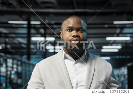 Admin in high tech data center doing maintenance to prolong gear life span and avoid downtime. African american server hub IT professional monitoring infrastructure supercomputers 137315201