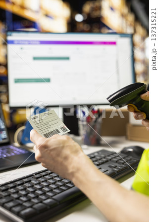 Asian depot employee scanning awb numbers for order processing and inventory control, using a scanner on shipping labels in the warehouse. Registering barcodes before distribution. 137315221