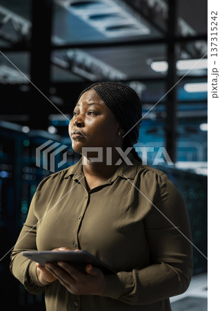Data center software developer installing and configuring hardware used for hosting digital services. African american server room worker testing and repairing rigs managing file transfers 137315242