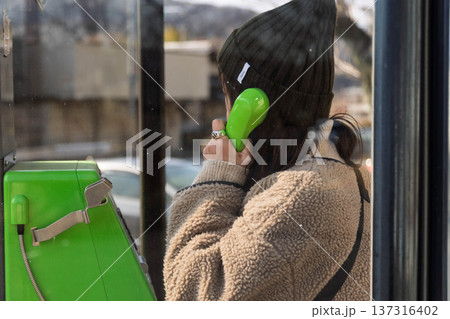 公衆電話をかける女性 137316402