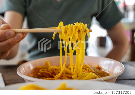 Someone try to eating Khao soi (Northern Thai Coconut Curry Noodle Soup). Khao soi is one of the most popular Thai dishes to eat in northern Thailand, especially in Chiang Mai and Chiang Rai. 137317203
