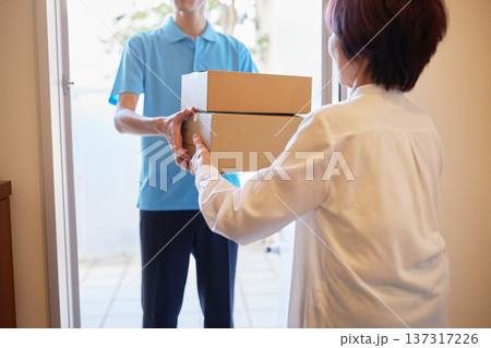 宅急便を受け取る女性と配送業者の男性 宅急便を受け取る女性と配送業者の男性 137317226