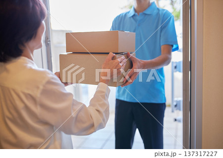 宅急便を受け取る女性と配送業者の男性 宅急便を受け取る女性と配送業者の男性 137317227