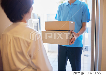 宅急便を受け取る女性と配送業者の男性 宅急便を受け取る女性と配送業者の男性 137317228
