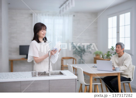 キッチンでお皿を拭きながら笑顔で話す60代女性と男性 137317282