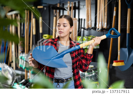 Female farmer choosing shovel in gardening store Female farmer choosing shovel in gardening store 137317911