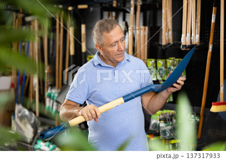 Man choosing shovel in store 137317933