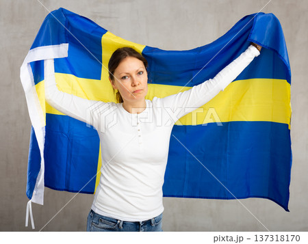 Sorrowful woman posing in studio with national flag of Sweden Sorrowful woman posing in studio with national flag of Sweden 137318170