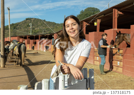 Portrait of young woman in front of stable and paddock for walking horses 137318175