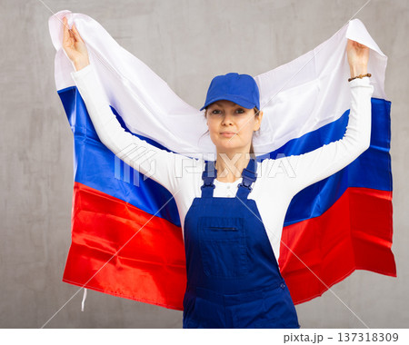 Cheerful female worker with wide grin on her face holding flag of russia Cheerful female worker with wide grin on her face holding flag of russia 137318309