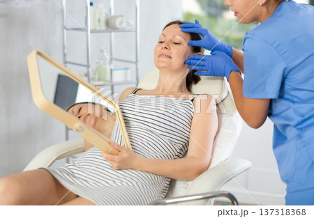 Young woman cosmetologists examines face of female patient 137318368