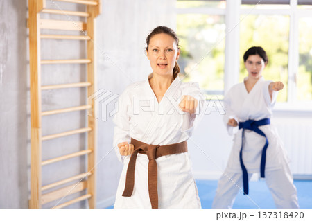 Woman in kimono standing in fight stance during group karate training 137318420