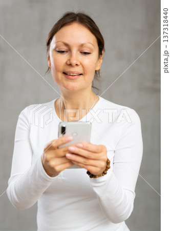 Smiling woman reading message on phone in studio Smiling woman reading message on phone in studio 137318440