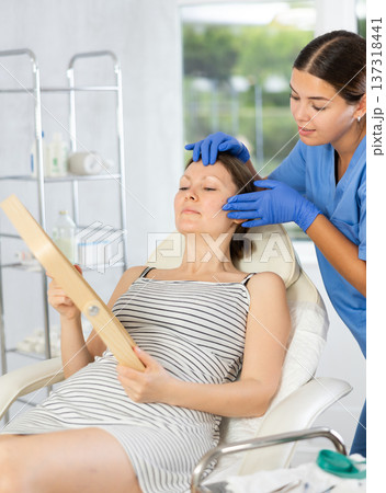 Cosmetologist examine patients contour face after lifting oval of face and palpate cheekbones Cosmetologist examine patients contour face after lifting oval of face and palpate cheekbones 137318441
