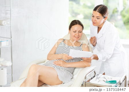 Woman doctor give patient medical documents for review before carrying out cosmetic procedure Woman doctor give patient medical documents for review before carrying out cosmetic procedure 137318447