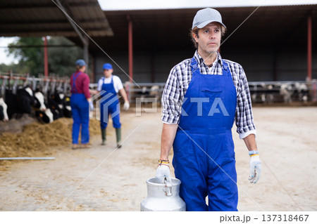 Adult male farmer with can works on dairy farm Adult male farmer with can works on dairy farm 137318467