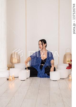 Healing meditation. Sound therapy. Woman playing crystal singing white bowls wellness retreat steam fire candles for spiritual treatment. Healing meditation. Sound therapy. Woman playing crystal singing white bowls wellness retreat steam fire candles for spiritual treatment. 137320744