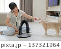 Asian woman feeling happy playing with pet cat inside living room home improving mental health and general wellness creating friendly environment with scratching toy 137321964