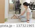 Calm asian woman sitting on floor inside comfortable home playing with friendly pet cat feeling happy promoting good mental health and daily wellness 137321965