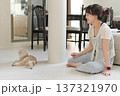 Happy asian woman sitting on indoor floor at home enjoying time with friendly pet cat promoting mental health wellness relaxing smiling expressing joyful positive emotion living room 137321970