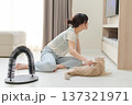 Happy asian woman using brush on friendly pet cat on floor at comfortable home improving mental health and everyday wellness during relaxing indoor activity for animal companion 137321971