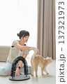 Relaxed asian woman gently petting friendly domestic cat at home promoting mental health wellness and positive emotional animal care bonding with furry feline pet sitting on floor 137321973