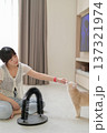 Relaxed happy asian woman petting friendly cat pet at home promoting mental health wellness and deep emotional relaxation sitting on floor near scratcher toy 137321974