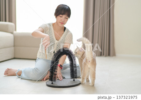 Smiling cheerful asian woman enjoying quality time playing with cute cat pet at cozy home promoting positive mental health and wellness in friendly relaxing environment Smiling cheerful asian woman enjoying quality time playing with cute cat pet at cozy home promoting positive mental health and wellness in friendly relaxing environment 137321975