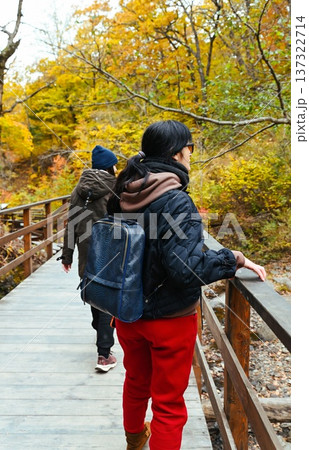 Two Russian female travelers walking on wooden bridge in autumn forest. Back view of friends hiking together, calm wellness journey and active travel lifestyle. Two Russian female travelers walking on wooden bridge in autumn forest. Back view of friends hiking together, calm wellness journey and active travel lifestyle. 137322714