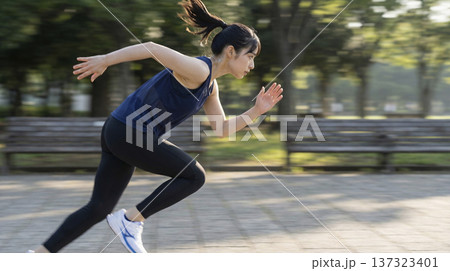 公園の路上で前を見つめ力強くダッシュをする日本人女性 公園の路上で前を見つめ力強くダッシュをする日本人女性 137323401