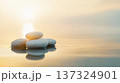 Smooth white stones stacked on calm water with serene sunset in background 137324901
