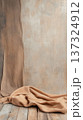 Neutral toned fabric draped on rustic wooden floor with textured beige wall background 137324912