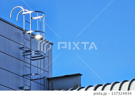 Minimal fixed aluminum ladder with a safety cage with blue sky background. Minimal fixed aluminum ladder with a safety cage with blue sky background. 137324934