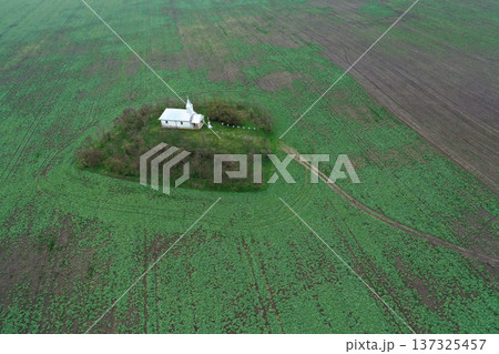 Aerial view of small white chapel in the middle of agricultural field Aerial view of small white chapel in the middle of agricultural field 137325457
