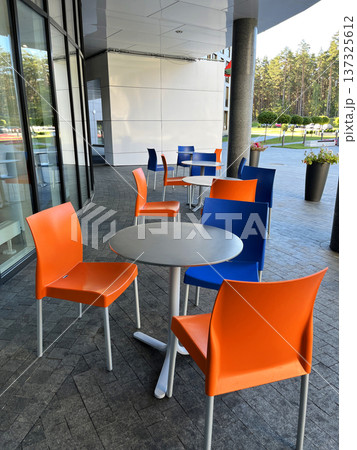 Orange and Blue Chairs and Round Tables in Street Cafe. 137325612