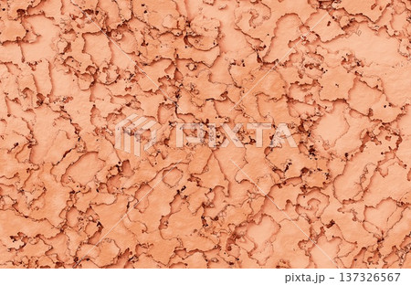 Peeling orange and peach paint layers on weathered surface creating abstract cracked clay texture. 137326567