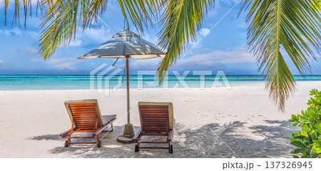 Picturesque sunny love couple sharing an intimate moment on beachfront sun beds under a shaded umbrella 137326945