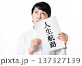 人生航路と書かれた紙を持ち斜め上に視線を投げる白いシャツを着たシニア女性 137327139
