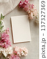 Blank vertical paper card with textured background framed by blooming pink and white flowers for an elegant invitation mockup 137327369