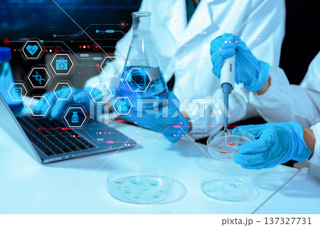 Scientists conducting research in a biotechnology lab, using pipettes and test tubes for medical and chemical experiments. Innovation in chemistry, healthcare, and medicine. Scientists conducting research in a biotechnology lab, using pipettes and test tubes for medical and chemical experiments. Innovation in chemistry, healthcare, and medicine. 137327731