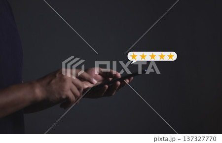 Review Customer, Young Man hand holding Smart Phone with five star to review and give 5 stars with very good results in service, Good review 5 star rating choice feedback 137327770